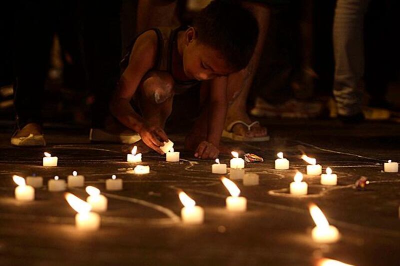 epa03012676 A Filipino boy lits a candle  to commemorate the second anniversary of the Maguindanao massacre near the gates of presidential palace in Manila, Philippines, 23 November 2011. Human rights activists and relatives of victims marked the second anniversary of the Maguindanao Massacre, when 32 journalists were killed on 23 November 2009 in what has been known as one of the worst election-related crimes in Philippine history.  EPA/DENNIS M. SABANGAN