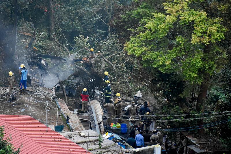 Firemen and rescue workers try to control the fire in the burning debris of the helicopter crash site.  AFP