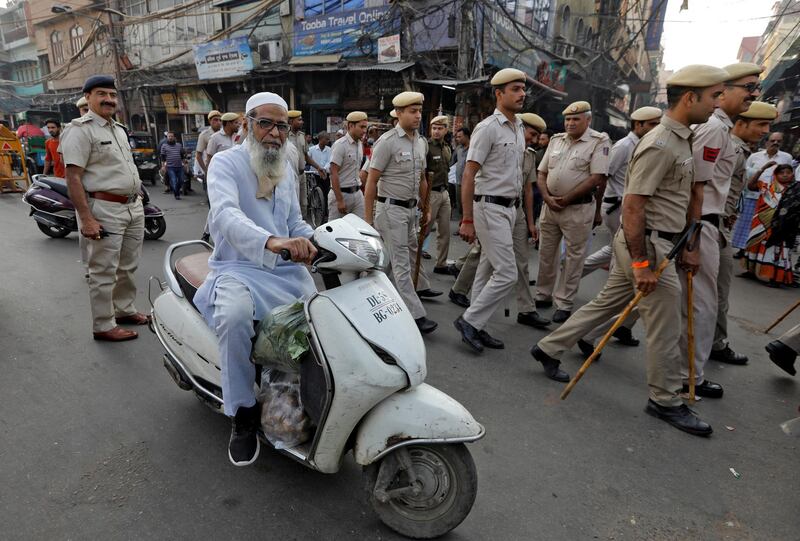 A man rides a scooter past police officers conducting outside the Jama Masjid in Delhi before Supreme Court's verdict on the disputed Ayodhya site. Reuters