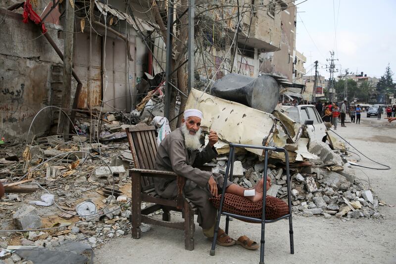 An injured man sits by the ruins of a house in Rafah, southern Gaza, following an Israeli strike. Reuters