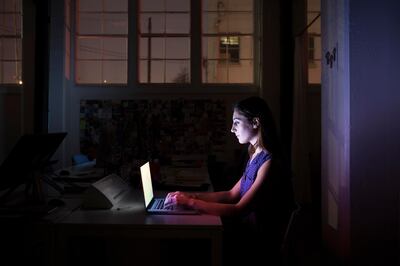 Young employee working late on computer in dark in creative office space. Getty Images