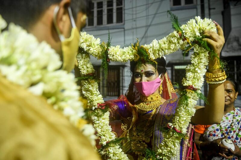 A bride exchanges flower garlands with a groom as part of a traditional ritual of their social marriage function, during a lockdown imposed by the state government against the surge in Covid-19 cases, in Kolkata, India. AFP