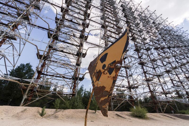 A rusty radioactivity warning sign sits beneath the inter-ballistic early warning radar system, known as Duga Radar, in the Chernobyl exclusion zone. Bloomberg