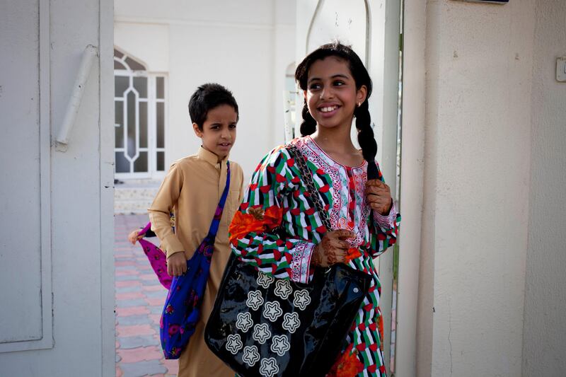 Sharjah, United Arab Emirates - June 23 2013 - (L-R) Cousins Abdullah Al Jabri, 9 and Hind Al-Suwaidi,10  leave a home in the Leyyah neighborhood of the city after collecting sweets. They are participating in Hag El Leila, an Emirati tradition that occurs every year 15 days before the start of the month of Ramadan. The tradition involves children walking from door-to-door singing and collecting sweets and money. (Razan Alzayani / The National) FOR RYM GHAZAL STORY  *** Local Caption ***  RA0623_hag_el_layla_006.jpg
