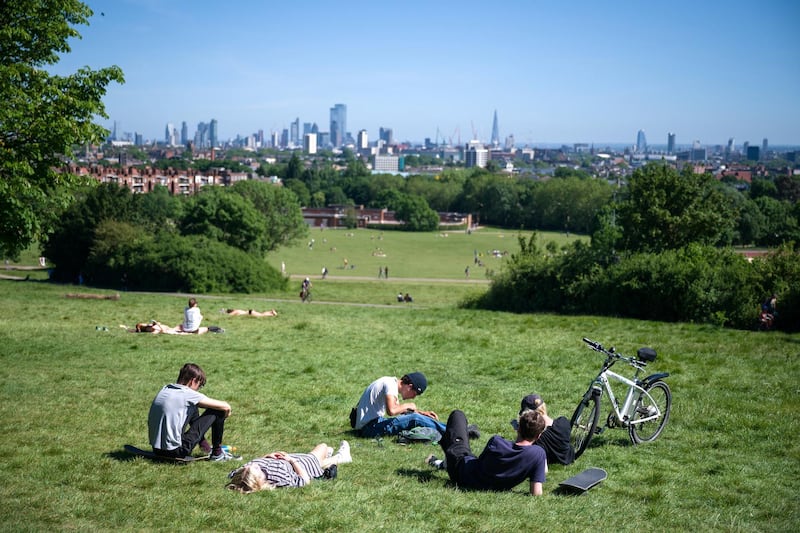LONDON, UNITED KINGDOM - MAY 29: People sunbathe and socialise on Parliament Hill on May 29, 2020 in London, England. From Monday, groups of up to six people from different households can meet in outdoor spaces, as long as they respect the correct social distancing guidelines. However, as the weather continues to stay at record high temperatures for this time of year, many have chosen to adopt the new guidelines early. The British government continues to ease the coronavirus lockdown by announcing schools will open to reception year pupils plus years one and six from June 1st. Open-air markets and car showrooms can also open from the same date.  (Photo by Leon Neal/Getty Images)