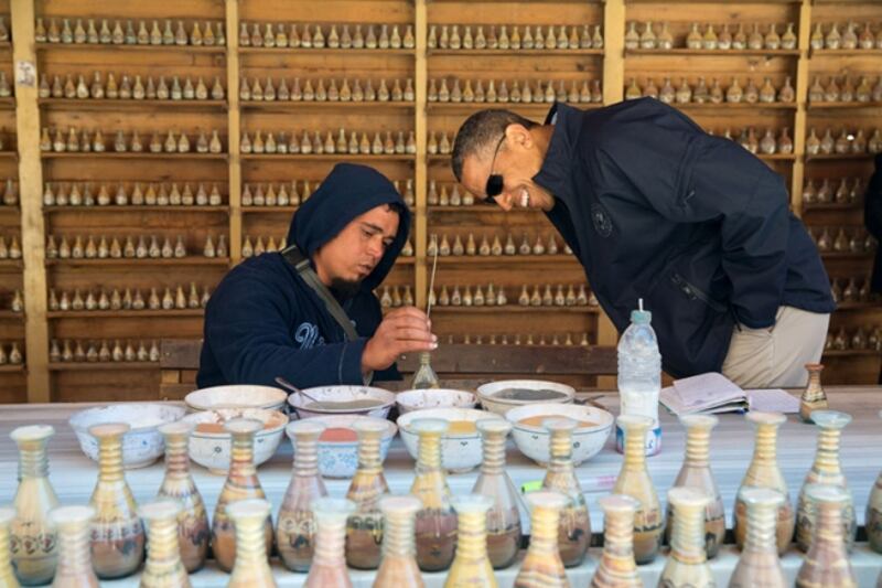 Mr Obama watches as a vendor writes a name using coloured sand in a bottle during a walking tour of the ancient city of Petra in Jordan, March 23, 2013. Photo: The National Archives