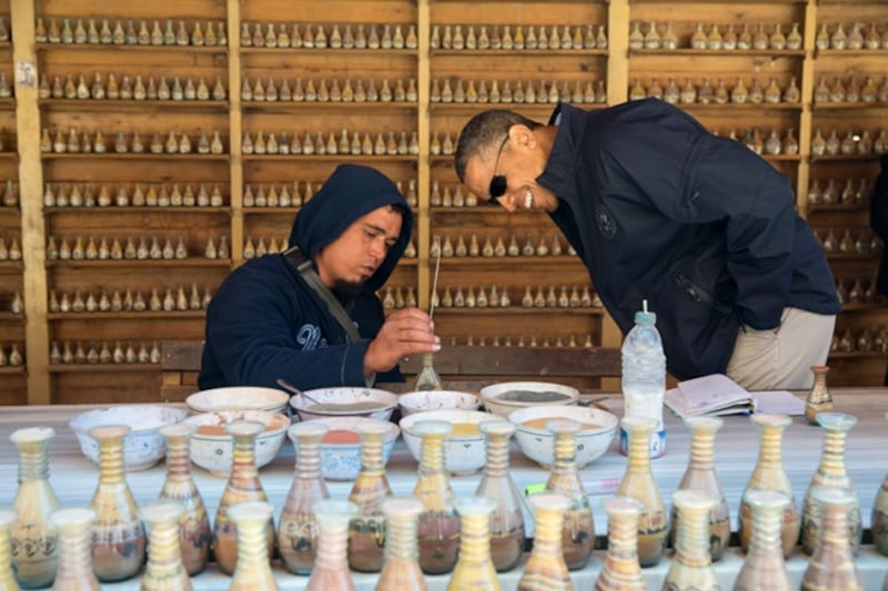 Mr Obama watches as a vendor writes a name using coloured sand in a bottle during a walking tour of the ancient city of Petra in Jordan, March 23, 2013. Photo courtesy of the National Archives