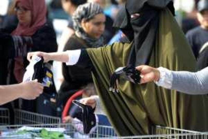 Samira, 36, wearing a niqab, the islamic full veil, buy socks at a market of Venissieux near Lyon, eastern France, on April 22, 2010. French government will pass a law to ban Muslim women from wearing a full-face veil in public, despite a warning from experts that such a law could be unconstitutional, it announced on April 21.      AFP PHOTO / PHILIPPE DESMAZES *** Local Caption ***  361307-01-08.jpg *** Local Caption ***  361307-01-08.jpg