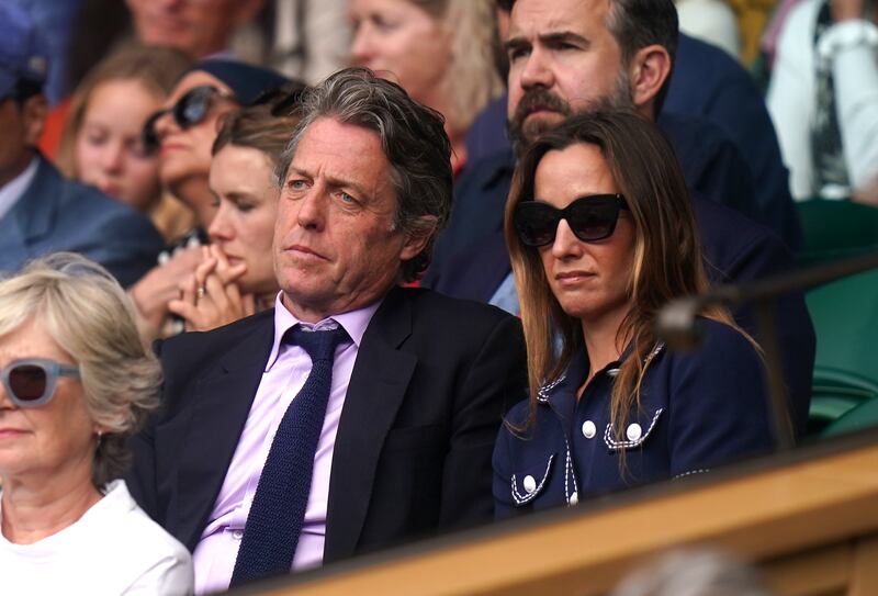 Hugh Grant and Anna Elisabet Eberstein in centre court on day nine of Wimbledon at The All England Lawn Tennis and Croquet Club, Wimbledon.