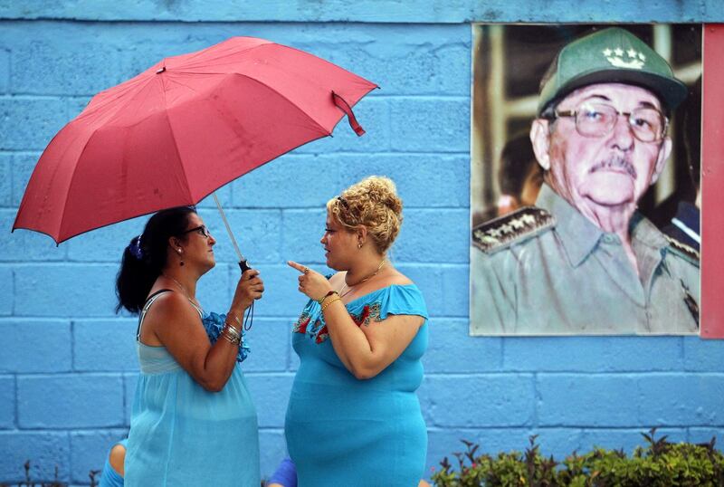 Two women talk in front of a Raul Catro's picture before the procession of the Virgin of Regla in Havana, Cuba.  EPA