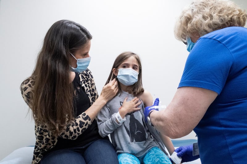 A child, 9, is held by her mother as she receives the second dose of the Pfizer vaccine during a clinical trial for children at Duke University in the US. In the UAE, those who are 16 and above are eligible to receive the vaccine.