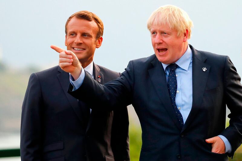 British Prime Minister Boris Johnson (R) gestures past French President Emmanuel Macron at the Biarritz lighthouse, southwestern France, ahead of a working dinner on August 24, 2019, on the first day of the annual G7 Summit attended by the leaders of the world's seven richest democracies, Britain, Canada, France, Germany, Italy, Japan and the United States. EU leaders rounded on US President Donald Trump over his trade threats at a G7 summit in France overshadowed by trans-Atlantic tensions and worries about the global economy. / AFP / POOL / Francois Mori
