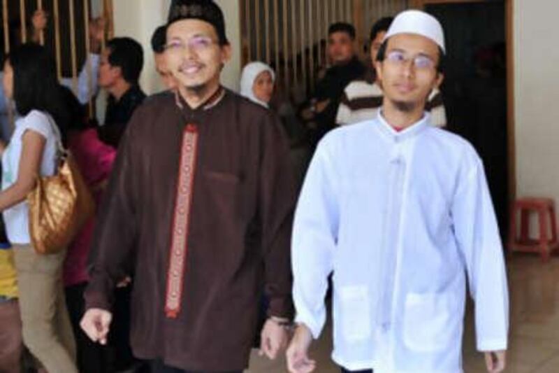 Agus Purwanto, left, and Parmin, two of three senior militants who allegedly aided top operatives from Jemaah Islamiyah JI, are escorted by plain clothes police before their trial at the Central Jakarta court on Oct 20 2008.