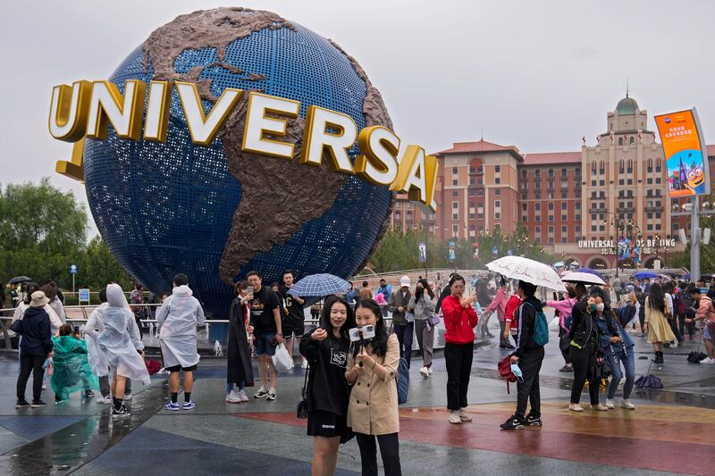 People take selfies near the entrance to Universal Studios Beijing in China on the opening day on September 20, 2021. AP Photo