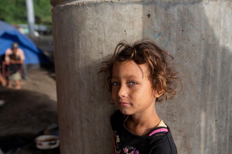 Katerine waits for breakfast cooked by her family under a bridge on the outskirts of San Pedro Sula, Honduras. The nine-year-old has lived under this bridge with her family since they lost their home to last year's hurricanes Eta and Iota in November. AP Photo