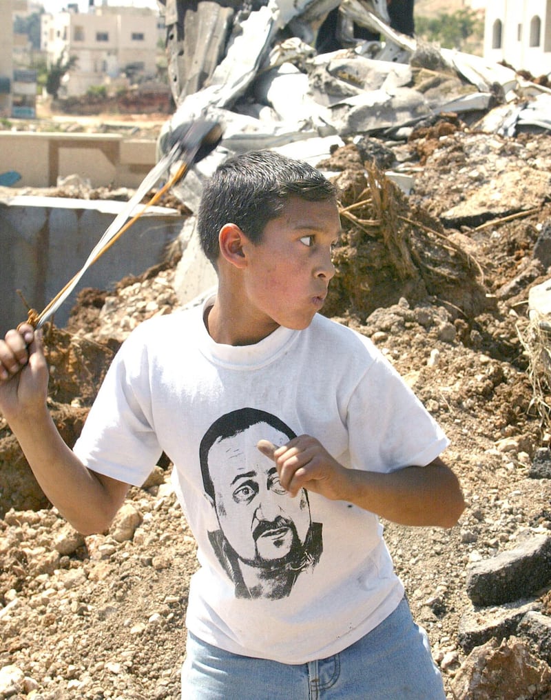 A Palestinian boy wearing a Barghouti T-shirt launches a stone at Israeli soldiers during clashes in May 2002 in Ramallah. AFP