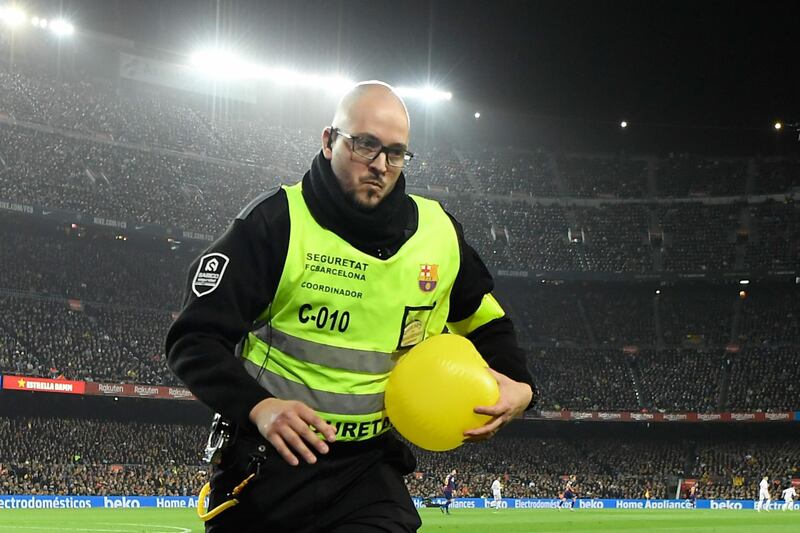 A security guard grabs a yellow ball thrown by a supporter. The protest help up the game briefly. AFP