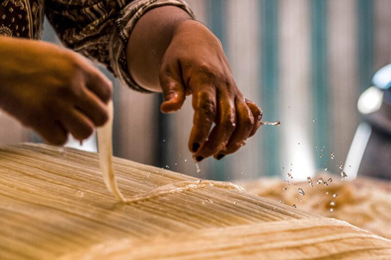 A woman prepares papyrus to compress and dry it.