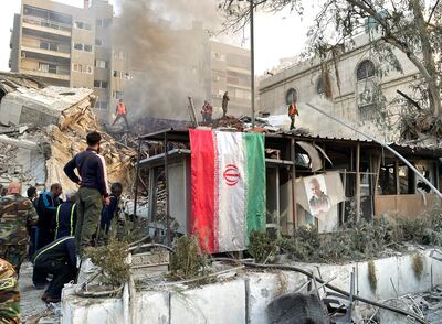 An Iranian flag hangs as smoke rises after what the Iranian media said was an Israeli strike on a the Iranian embassy compound in Damascus, Syria. Reuters