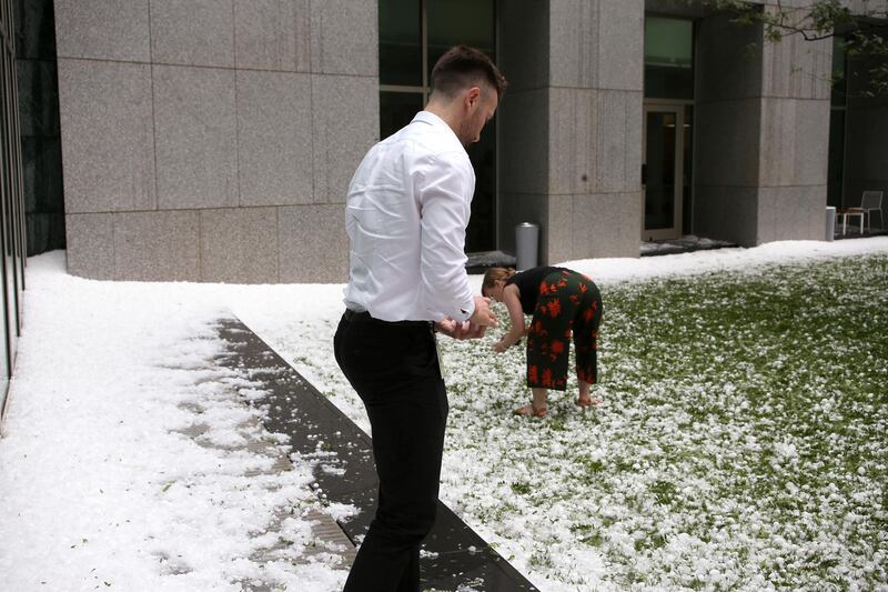 A man and woman collect golfball-sized hail on the grounds of Parliament House in Canberra, Australia, after a storm battered the Australian capital. AP Photo