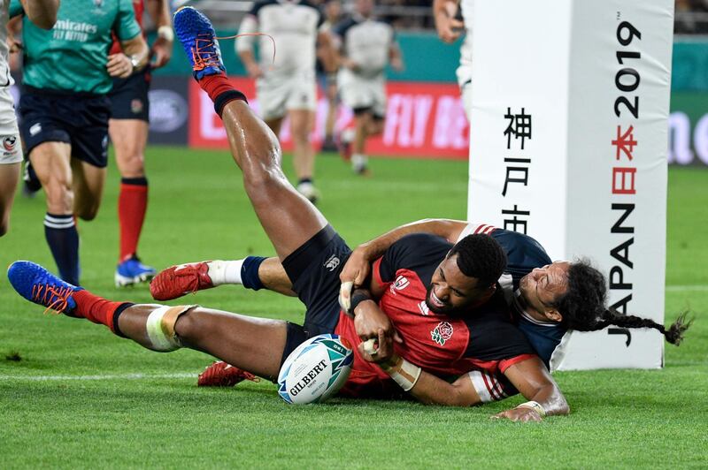 England wing Joe Cokanasiga, centre, scores a try during the Pool C match against the US. AFP