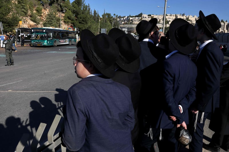 Ultra Orthodox Jewish youths watch Israeli security forces working at the scene of an explosion at a bus stop in Jerusalem. AFP