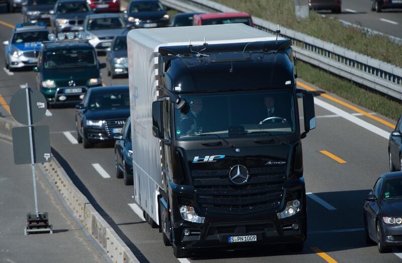 A Mercedes-Benz Actros truck equipped with a highway pilot automated self-driving system drives on the A8 highway in Denkendorf, southern Germany, on October 2, 2015 (at R is seen on the wheel Wolfgang Bernhard, Daimler board member for trucks and buses, at L is Baden-Wuerttemberg's State Premier Winfried Kretschmann). The highway pilot system for autonomous driving uses cameras, radar and assistance systems to maintain the lane position and following distance. In critical situations, the system gives alert to the driver to steer the truck himself again. If he doesn't, the vehicle can bring itself to a stop.           
 AFP PHOTO / DPA / MARIJAN MURAT   +++    GERMANY OUT    +++ / AFP PHOTO / DPA / MARIJAN MURAT