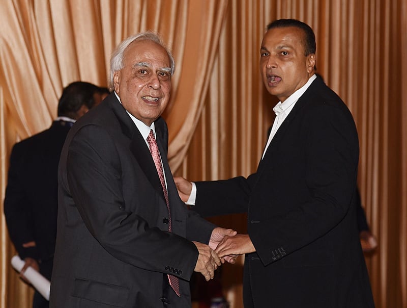 Indian politician Kapil Sibal (L) and Anil Ambani (R) greet each other at the reception