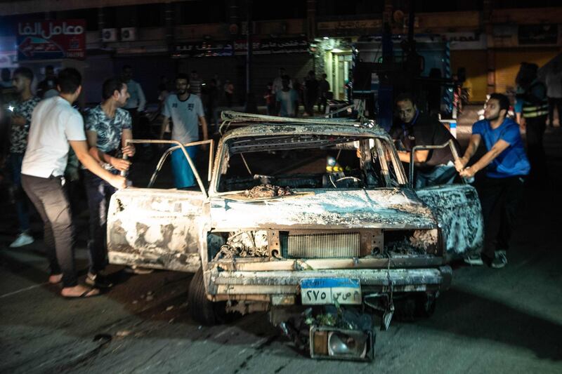 People surrounding a burned car after the explosion in downtown Cairo. AFP