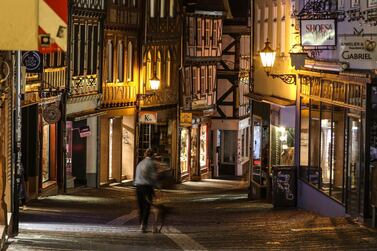 A man walks his dog in Old Town just before the nighttime curfew begins, in Marburg, Germany. Europe is enduring a third wave of the pandemic. Associated Press