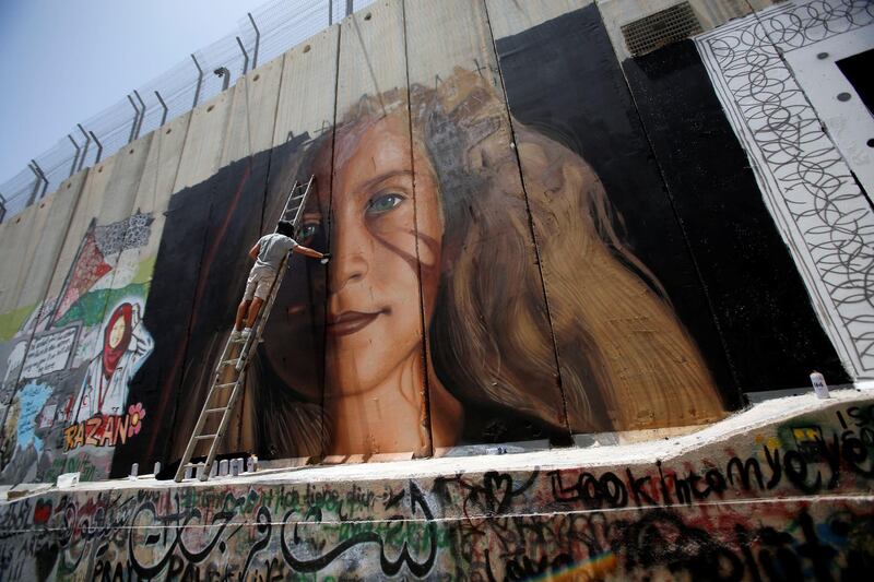 A foreign artist paints on the Israeli wall a mural depicting Palestinian teen Ahed Tamimi who is detained by Israel, in Bethlehem, in the occupied West Bank, July 25, 2018. REUTERS/Mussa Qawasma  NO RESALES. NO ARCHIVE.