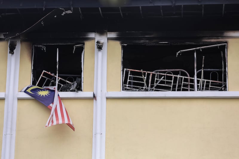 A Malaysian national flag and a burning bed are visible in the window of school room after a fire broke out at a religious school in Kuala Lumpur, Malaysia. Fazry Ismail / EPA