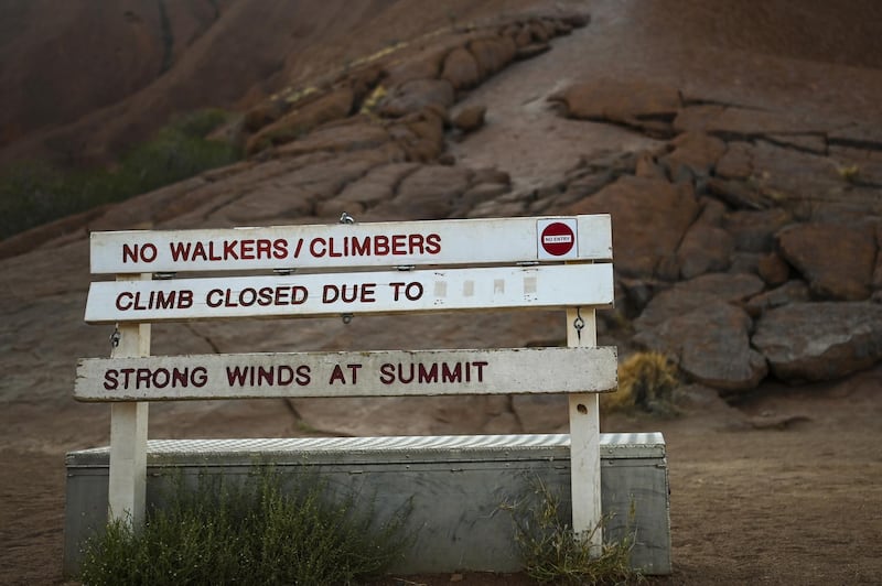 The sign at the bottom of the climb area indicates the climb is closed due to 'strong winds at summit at Uluru. EPA