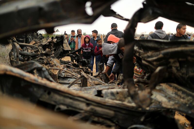 Palestinians gather around the remains of a vehicle that was destroyed. Reuters