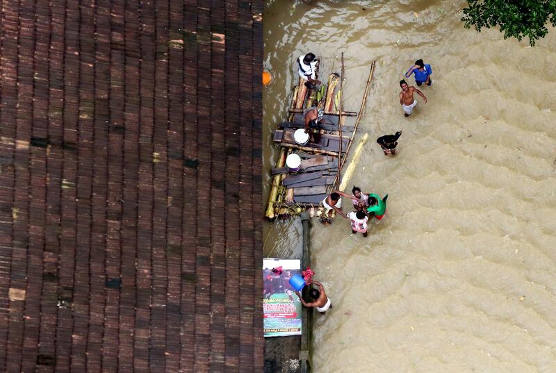 People wait for aid next to makeshift raft at a flooded area in the southern state of Kerala, India, August 19, 2018. REUTERS/Sivaram V