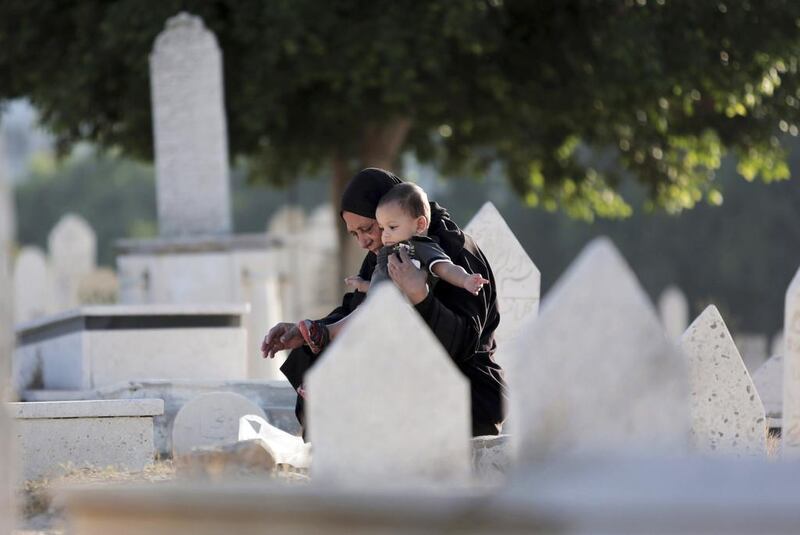 A Palestinian woman holds a child as she pays her respects at a relative's grave in a cemetery in Gaza City on Saturday. Khalil Hamra / AP Photo