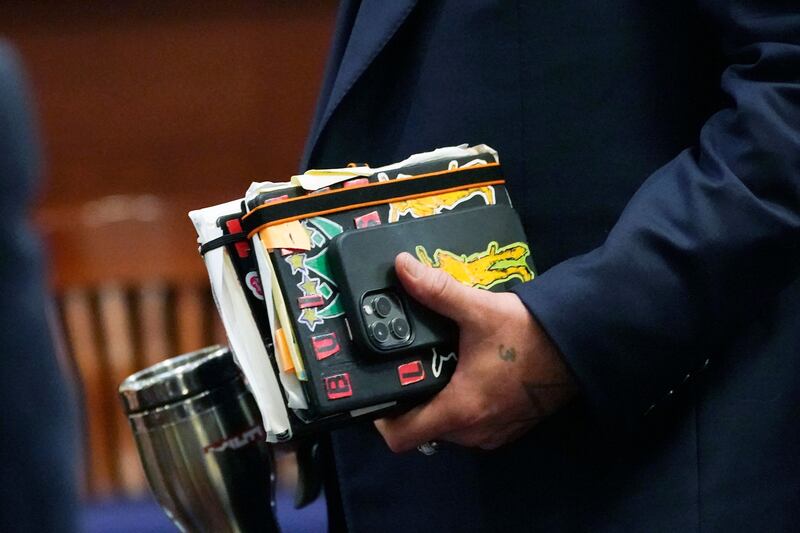 Depp carries his notebook and phone in the courtroom. AFP