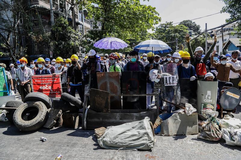 Protesters take cover behind a makeshift barrier during an anti-coup protest following the military crackdown in Yangon, Myanmar. EPA