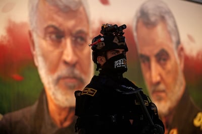 A member of Iraq's Hashed Al Shaabi on guard in front of a banner depicting assassinated Iraqi commander Abu Mahdi Al Muhandis, left, and Iranian Islamic Revolutionary Guard Corps commander Gen Qassem Suleimani, near Baghdad's International Airport on January 2, 2023 during a ceremony marking the third anniversary of their deaths. AFP
