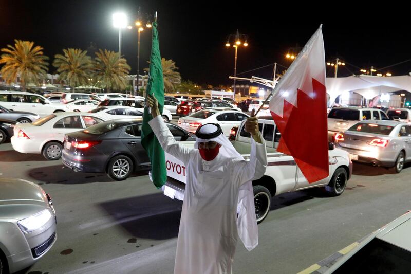 A Bahraini man holding Saudi and Bahraini national flags welcomes Saudis as they enter Bahrain on the King Fahd Causeway after Saudi Arabia lifted a 14-month-long travel ban on its citizens on May 17, 2021. Reuters