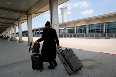 A departing passenger rolls his suitcases at the nearly deserted Ben Gurion airport in Lod, near Tel Aviv, on May 13, 2021.  Israel's civil aviation authority said it had diverted all incoming passenger flights headed for Ben Gurion airport to Ramon airport in the south, due to rocket fire from Gaza early in the morning. / AFP / GIL COHEN-MAGEN

