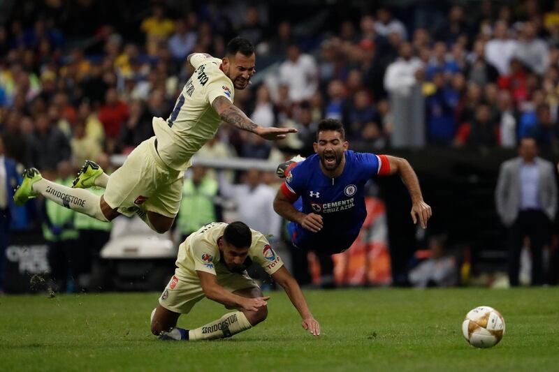 Cruz Azul's Edgar Mendez, right, and America's Victor Aguilera, left, fall as they fight for the ball during the Mexico soccer league first leg final match at Azteca stadium in Mexico City. AP Photo