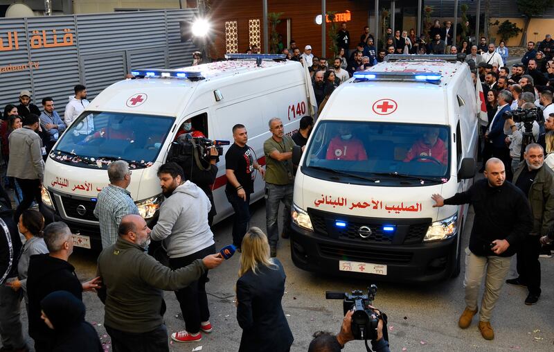 Colleagues and relatives of the killed journalists gather beside Lebanese Red Cross ambulances bearing the bodies of the two men. EPA