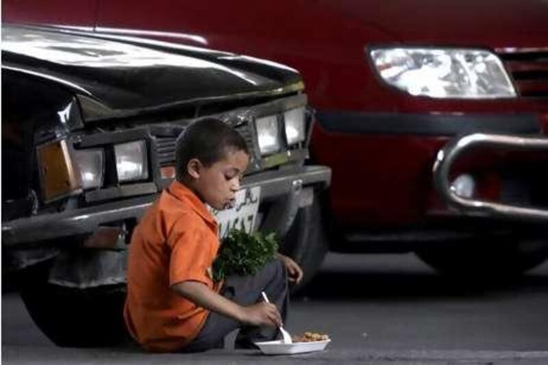 A street child eats on the side of the road on Wednesday in Cairo.