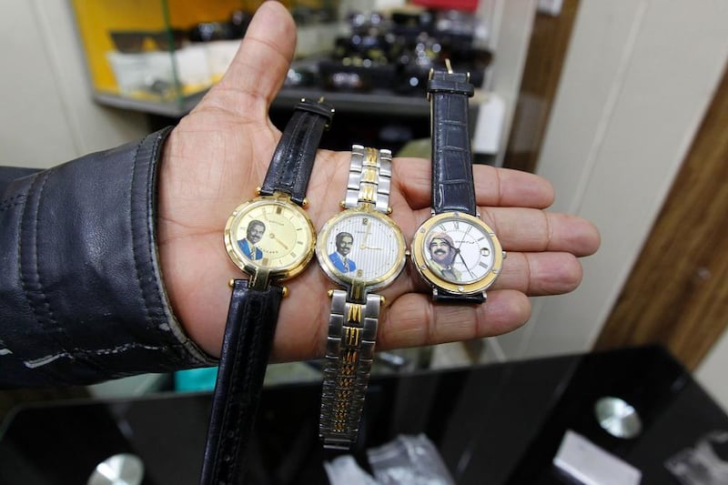 Iraqi shopkeeper Anwar holds wristwatches bearing portraits of Saddam Hussein at his Baghdad shop. Sabah Arar / AFP