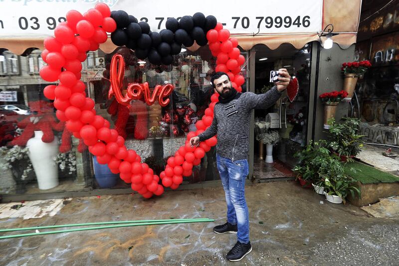 A Lebanese flowers vendor takes a selfie in front of his shop decorated for Valentine's Day in Beirut on February 13, 2018. / AFP PHOTO / JOSEPH EID