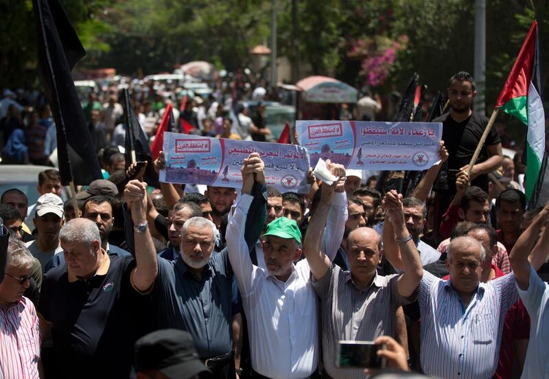 Head of the Hamas political bureau, Ismail Haniyeh, third from left, and Hamas leader in the Gaza Strip Yahya Sinwar raise their hands up with leaders of the other Palestinian factions as they attend a protest against the conference in Bahrain, which focuses on the economic portion of the White House's long-awaited plan for Mideast peace, in Gaza City, Wednesday, June 26, 2019. (AP Photo/Khalil Hamra)