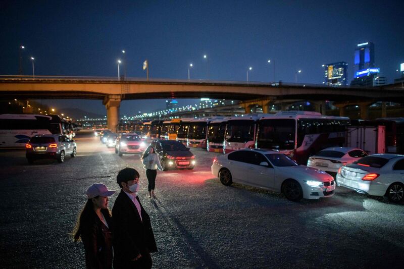 A couple walk between cars queuing for a screening at a drive-through cinema in Seoul. AFP