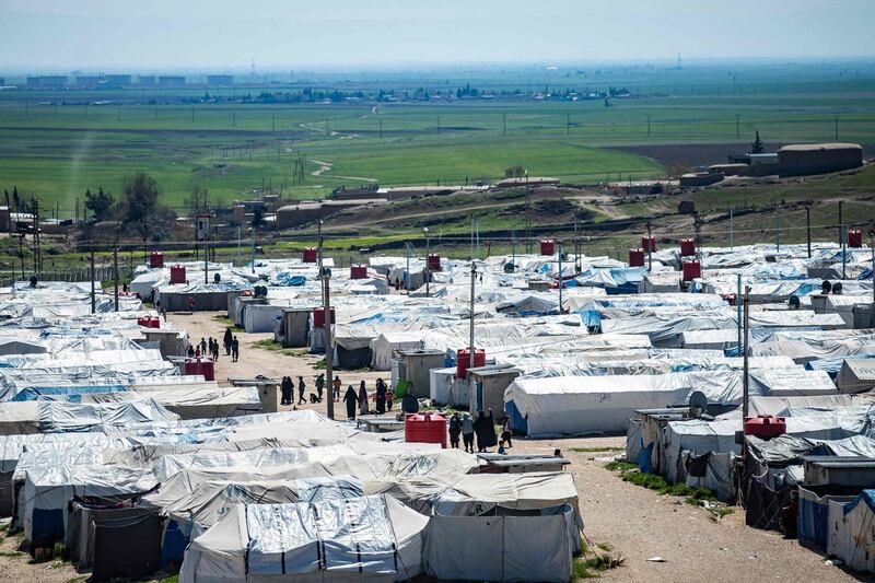 Women and children walk at Camp Roj, where relatives of people suspected of belonging to the Islamic State (IS) group are held, in the countryside near al-Malikiyah (Derik) in Syria's northeastern Hasakah province, on March 28, 2021. Roj, one of two Kurdish-run displacement camps housing foreign family members of suspected IS fighters, is smaller and better guarded than its overcrowded counterpart Al-Hol, which has been rocked by assassinations and breakout attempts in recent months.  / AFP / Delil SOULEIMAN
