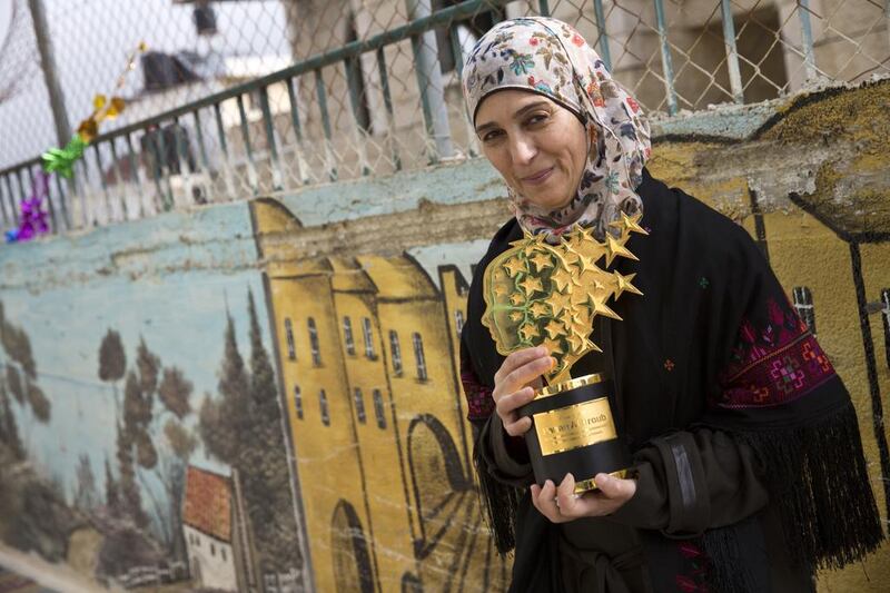 Hanan Al Hroub holds her Global Teacher trophy in the Samiha Khalil schoolyard in Al Bireh, just outside Ramallah on March 20, 2016. Her teaching philosophy is “to live in peace, to each in peace and teach peace”. Heidi Levine for The National